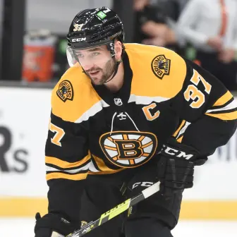 NHL athlete Patrice Bergeron skating with the puck for the Boston Bruins