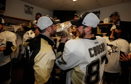 Sidney Crosby pouring a drink from the Stanley cup into Andy O'Briens mouth.