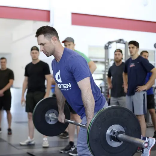 Andy O'Brien deadlifting while athletes watch him.