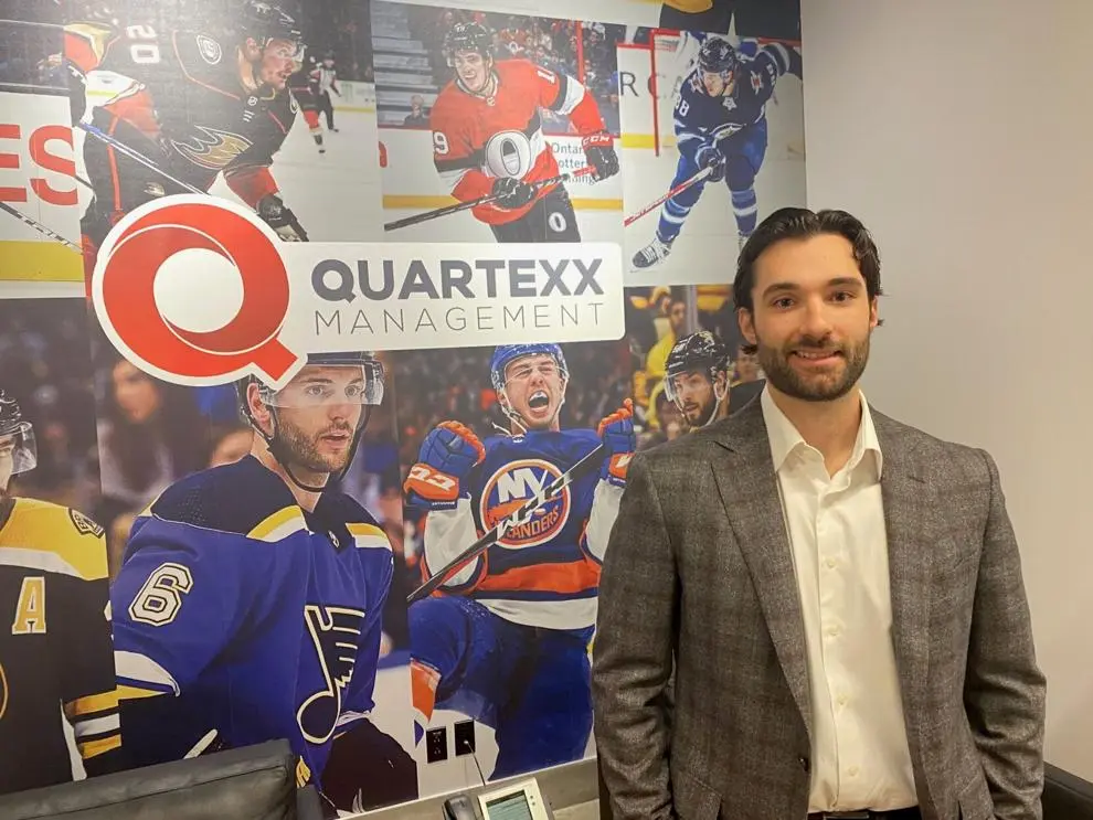 Giordano Saputo posing for a photo in front of a Quartexx Management player collage
